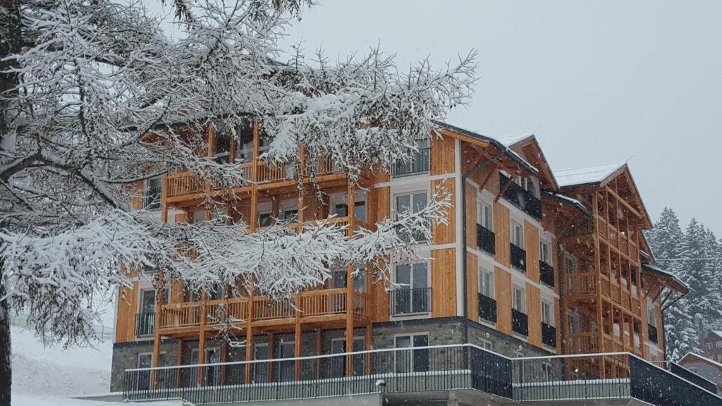 a large wooden building with snow on it at Kovárna Residence in Pec pod Sněžkou