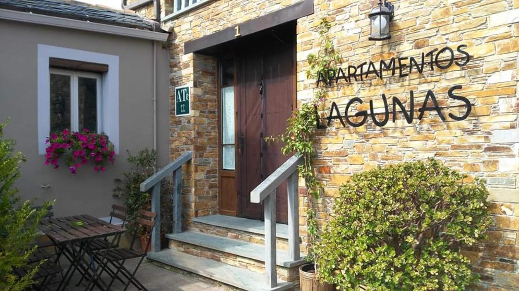 un edificio de ladrillo con una puerta de madera y escaleras en Apartamentos lagunas, en Castropol