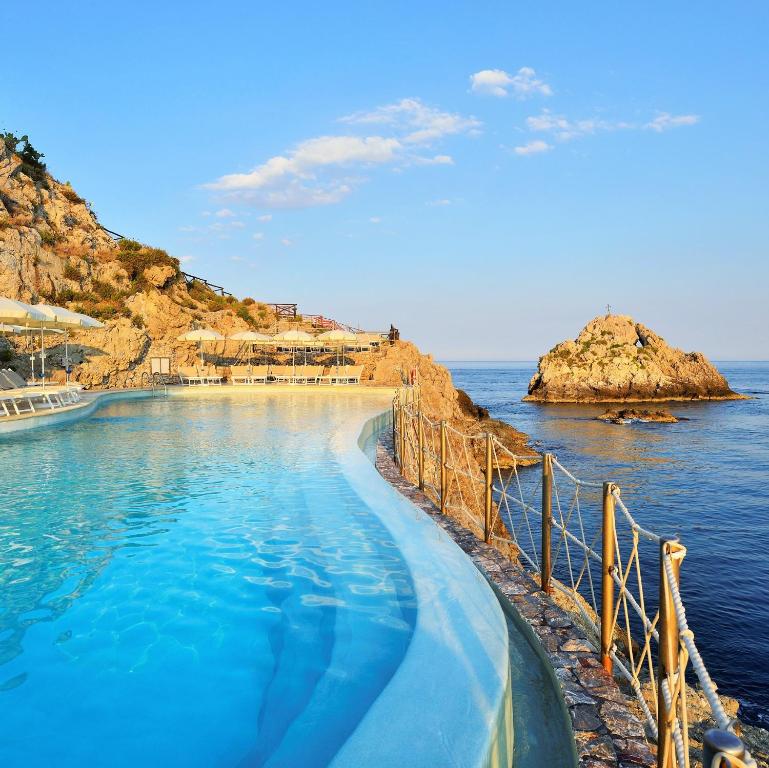 a swimming pool in the water next to the ocean at UNA HOTELS Capotaormina in Taormina