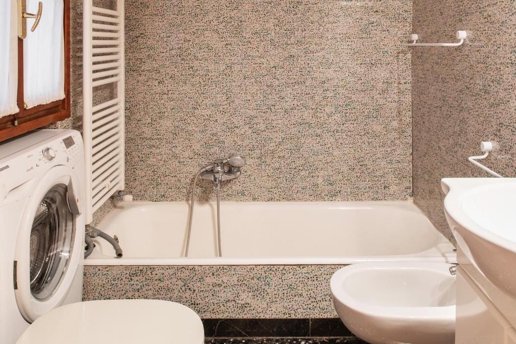 een badkamer met een wastafel, een bad en een wasmachine bij Ca’Molin in Venetië