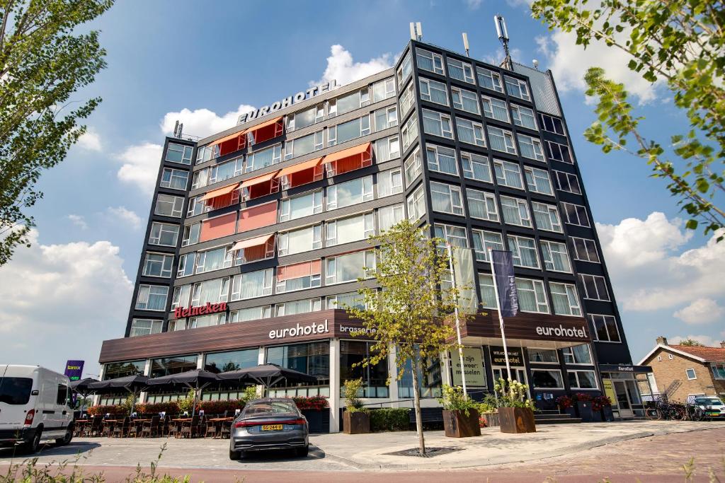 un edificio alto con coches estacionados frente a él en Eurohotel, en Leeuwarden