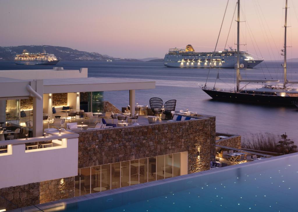 a cruise ship in the water next to a building at Mykonos Riviera Hotel & Spa, a member of Small Luxury Hotels of the World in Tourlos