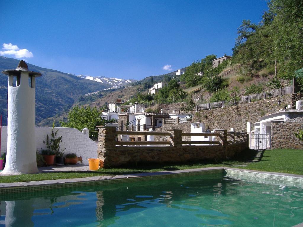 a house with a swimming pool in front of a mountain at Estrella de las Nieves in Pampaneira