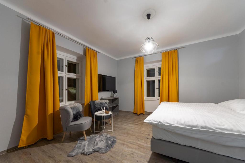 マラー・モラーヴカにあるHotel pod Kapličkouのベッドルーム(黄色いカーテン、ベッド、椅子付)