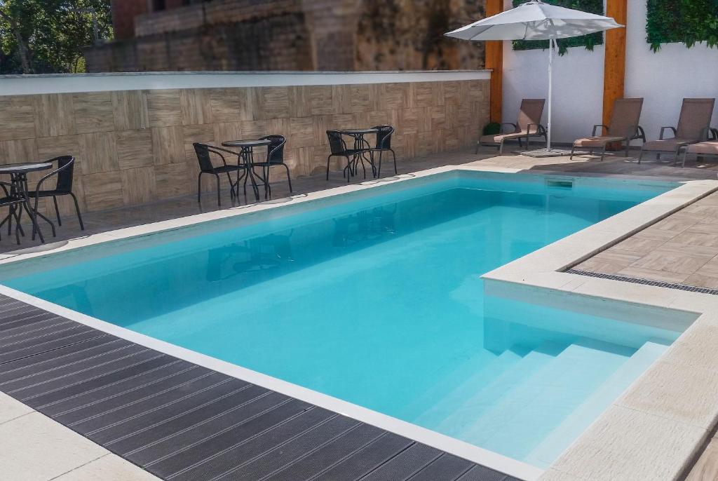 ein blauer Pool mit Stühlen und einem Sonnenschirm in der Unterkunft Hotel Rosa Mística by Umbral in Fátima