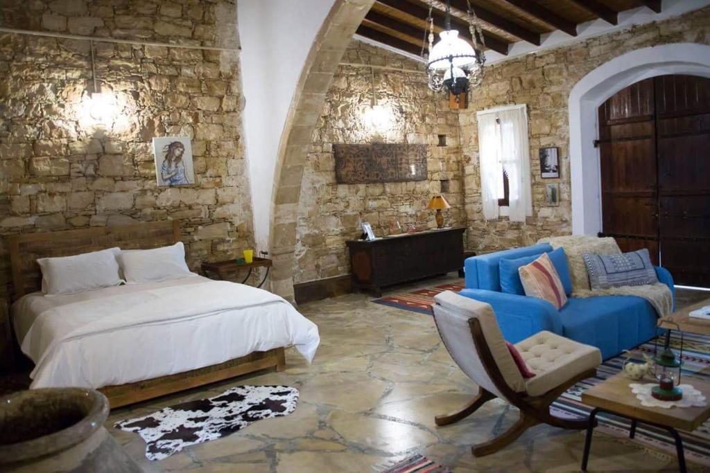a bedroom with a bed and a stone wall at Kazani House Lofou in Lofou