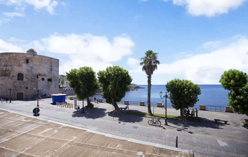 a street with trees and a building next to the ocean at Ciutat Alghero in Alghero