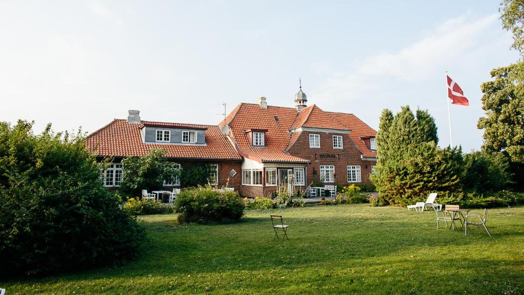 duży dom z flagą na dziedzińcu w obiekcie Langebjerg Pension & Spisested w mieście Allinge