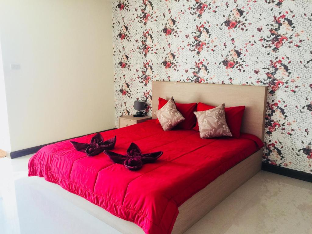 a bedroom with a red bed with black bows on it at Thani Residence in Chon Buri