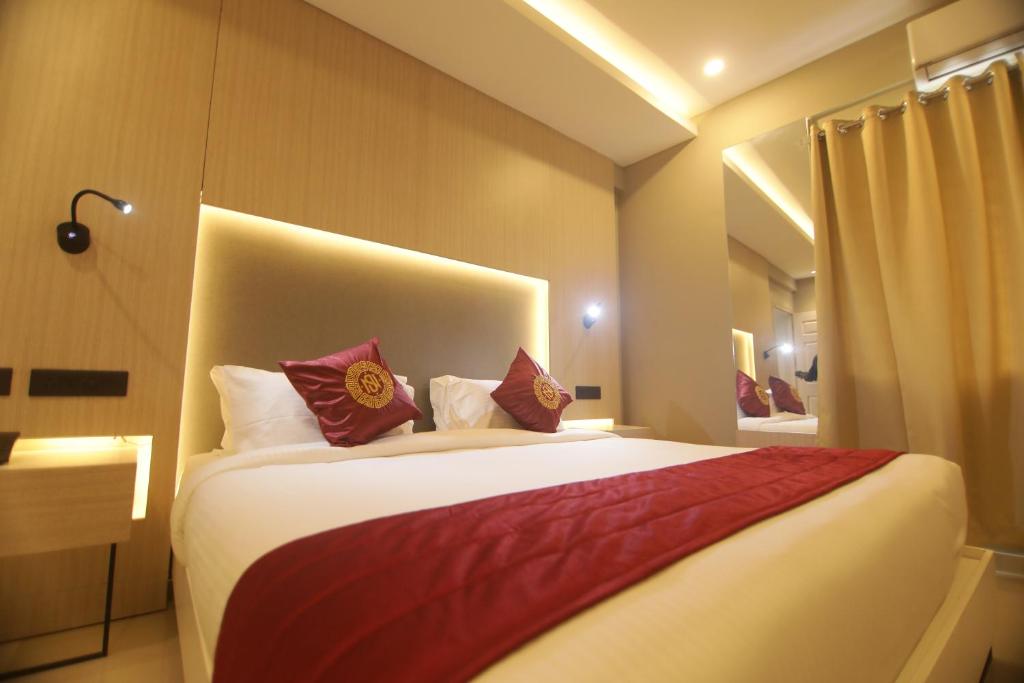 a bedroom with a large bed with red and white pillows at Noor jehan's Grand Noor in Palakkad