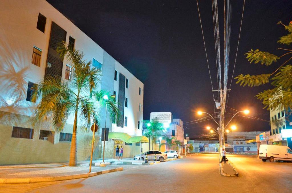 a city street at night with palm trees and buildings at Pousada Central in Feira de Santana