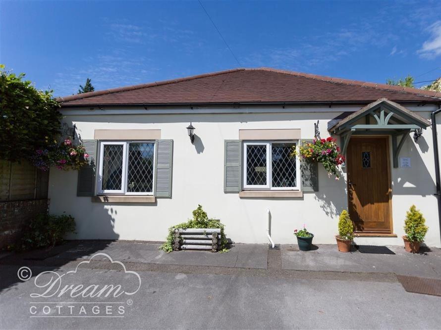 Casa blanca con puerta y ventanas marrones en Toll Lodge en Frampton