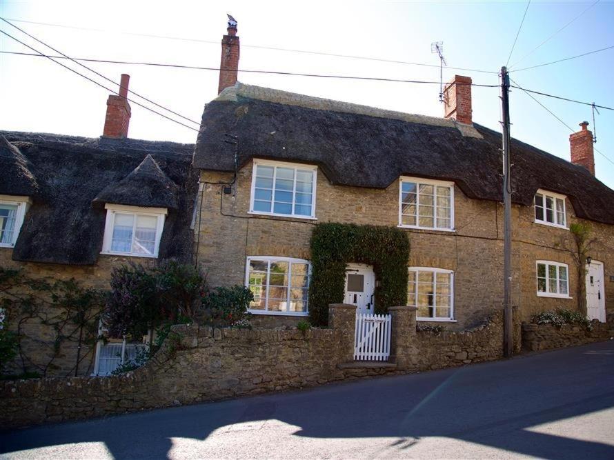 a large brick house with a thatched roof at Bramble Cottage in Burton Bradstock