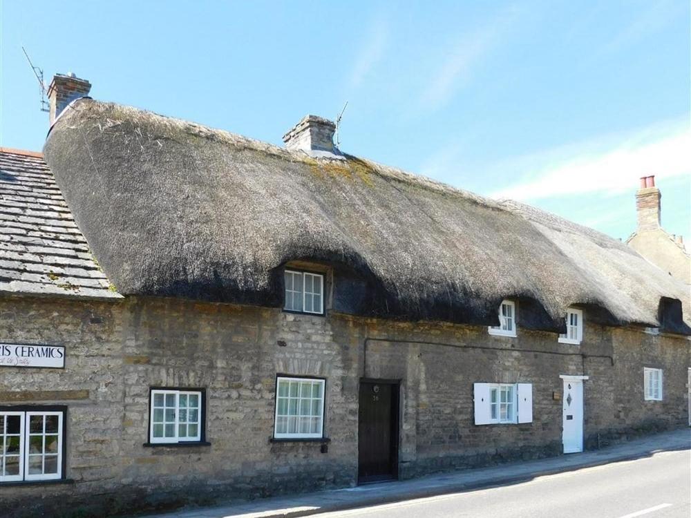 an old stone building with a thatched roof at Farrier's Lodge in Corfe Castle