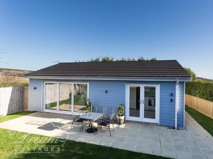 a small blue shed with a table and chairs at Outlook Lodge in Weymouth