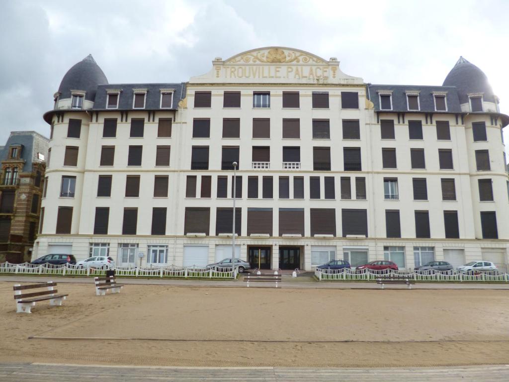 un gran edificio blanco con un cartel. en Paradis les pieds sur le sable trouville palace en Trouville-sur-Mer