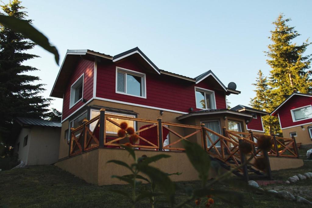 ein rotes Haus mit einem Balkon mit einem Teddybär darauf in der Unterkunft Cabañas Las gemelas de Puelo in Las Golondrinas