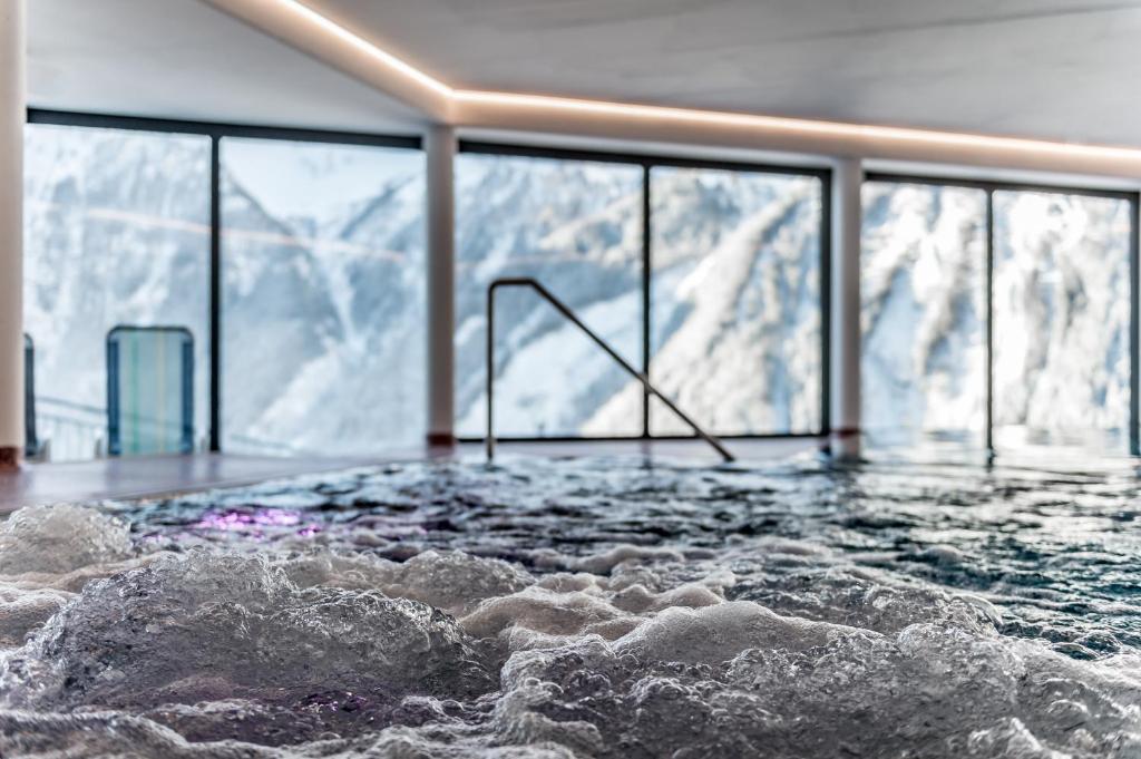 a jacuzzi tub with a view of a mountain at Hotel Burgstein - alpin & lifestyle in Längenfeld