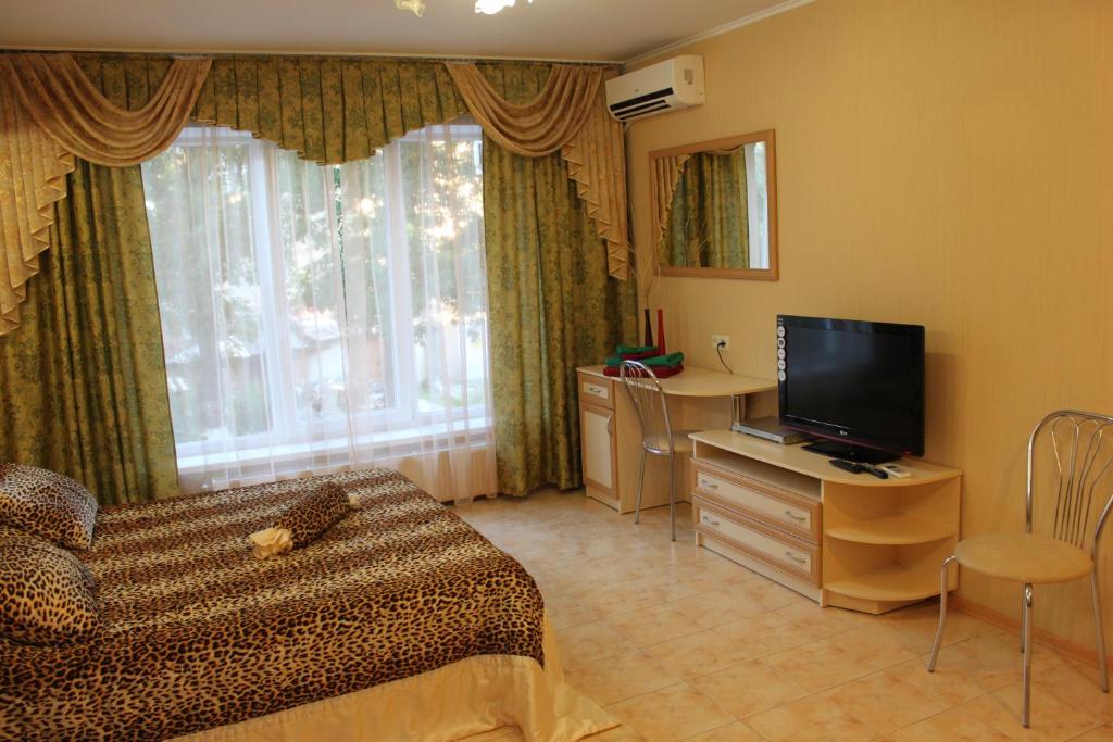 a room with a bed and a television and a chair at Guest House Gorkogo in Simferopol