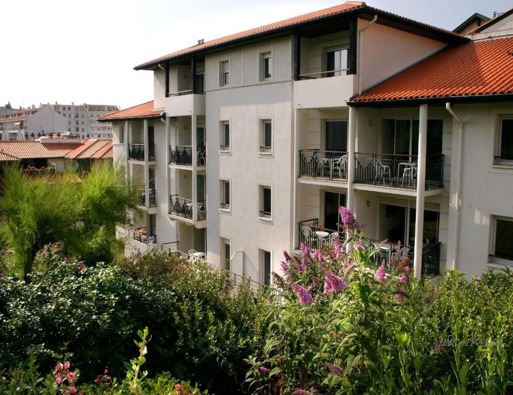 een wit appartementencomplex met een rood dak bij Résidence Biarritz Ocean in Biarritz