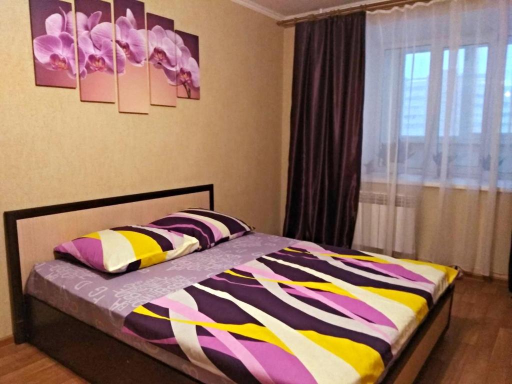 ペンザにあるApartment Proezd Rakhmaninova 3のベッドルーム1室(カラフルな毛布、窓付)