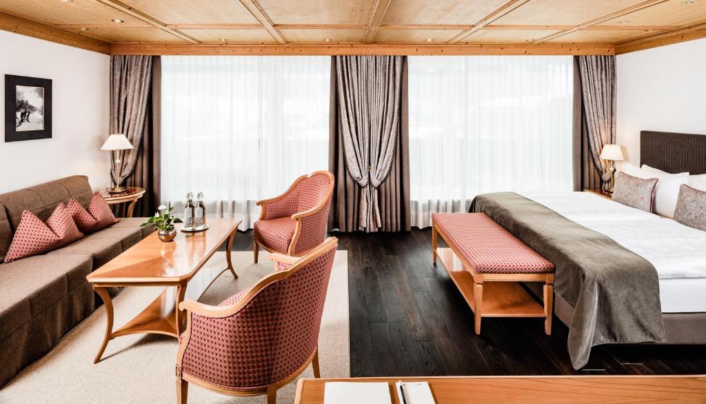 a hotel room with a bed and a couch at Hotel Alpenroyal - The Leading Hotels of the World in Selva di Val Gardena