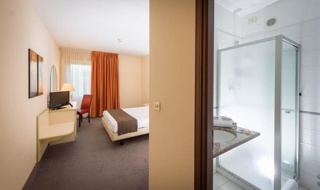 a hotel room with a bed and a bathroom at Hotel Des Alpes in Rosta