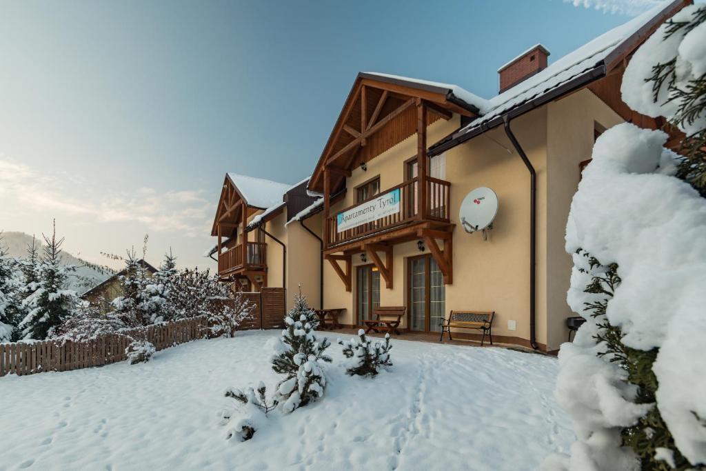 a house with a balcony in the snow at Apartamenty Tyrol in Szczawnica