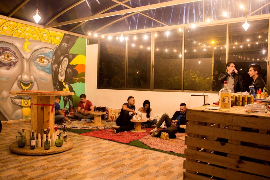 eine Gruppe von Menschen, die in einem Raum mit einem Gemälde sitzen in der Unterkunft Bababuy Hostel in Bogotá