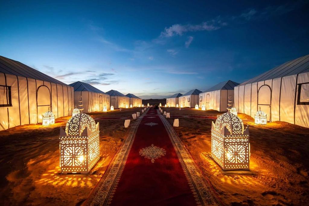 a row of buildings with lights on a red carpet at Sahara Happy Camp in Merzouga