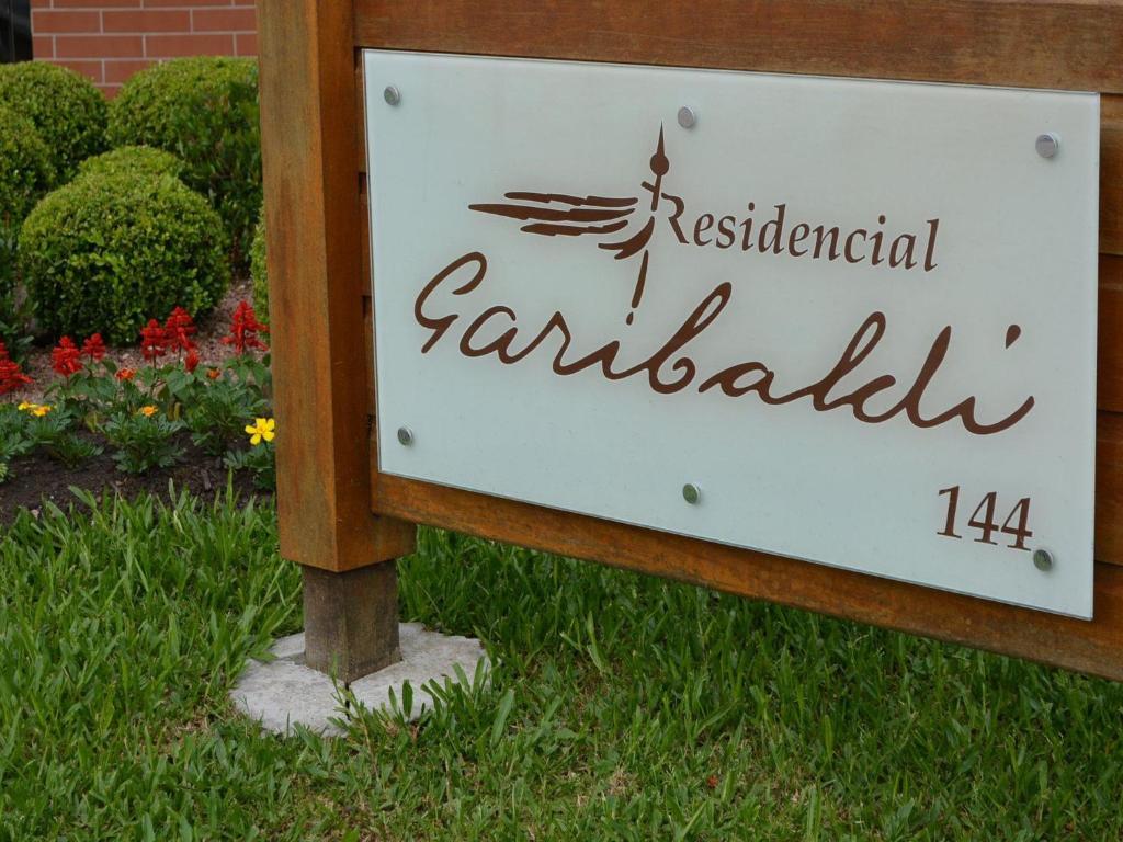 una señal para un jardín con flores al fondo en LOCAR-IN GRAMADO Residencial Garibaldi Centro, en Gramado