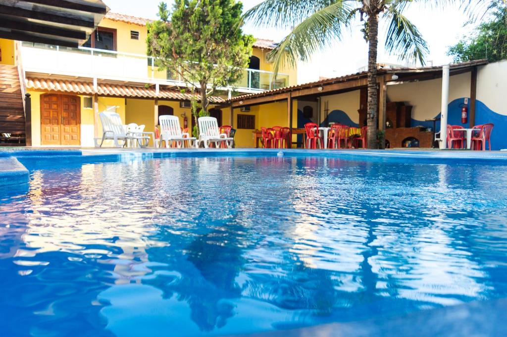 a large swimming pool with chairs and tables in front of a house at Pé N'Areia in Cabo Frio