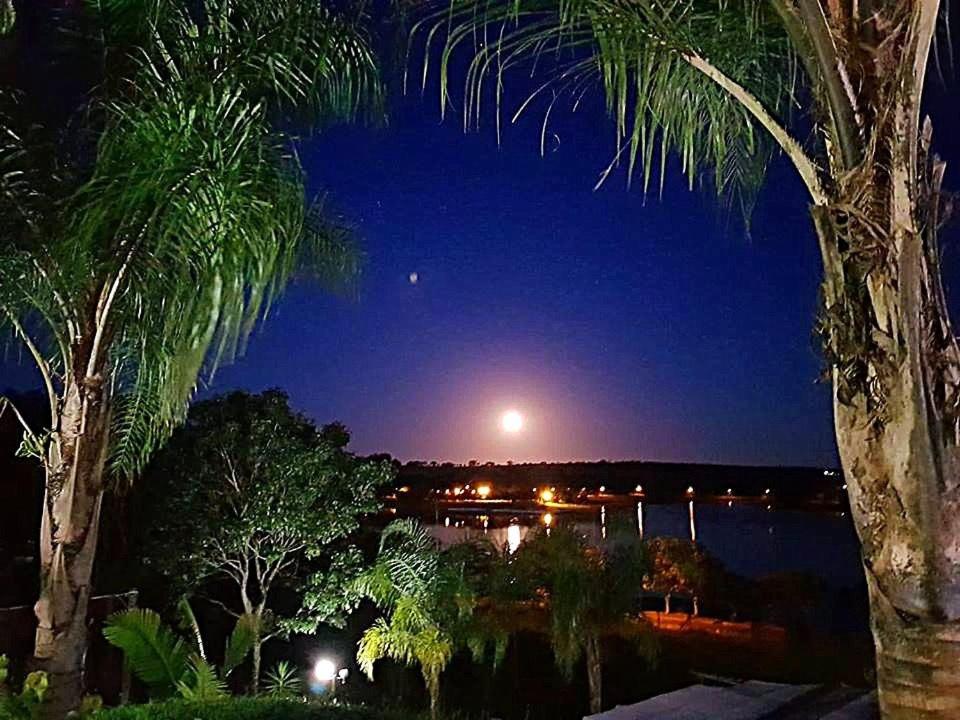 een volle maan die 's nachts boven een stad opkomt bij Rancharia Park Hotel in Rancharia