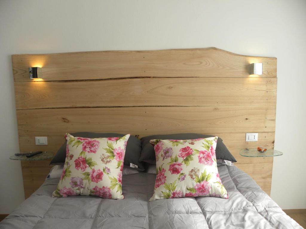 a bed with two pillows and a wooden headboard at Corte Del Gallo in Corniglia