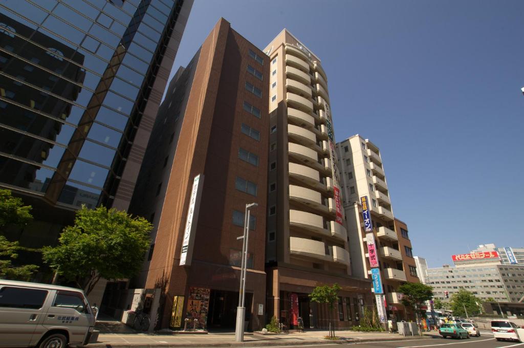 un grand bâtiment dans une rue de la ville avec des bâtiments dans l'établissement Hotel Route-Inn Sapporo Ekimae Kitaguchi, à Sapporo