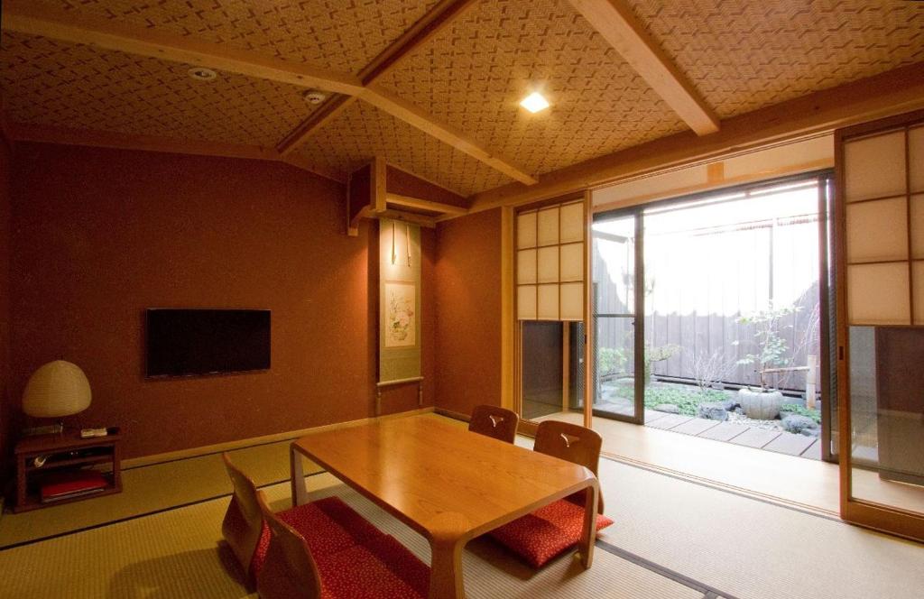 a dining room with a table and chairs and a window at Akane an Machiya House in Kyoto