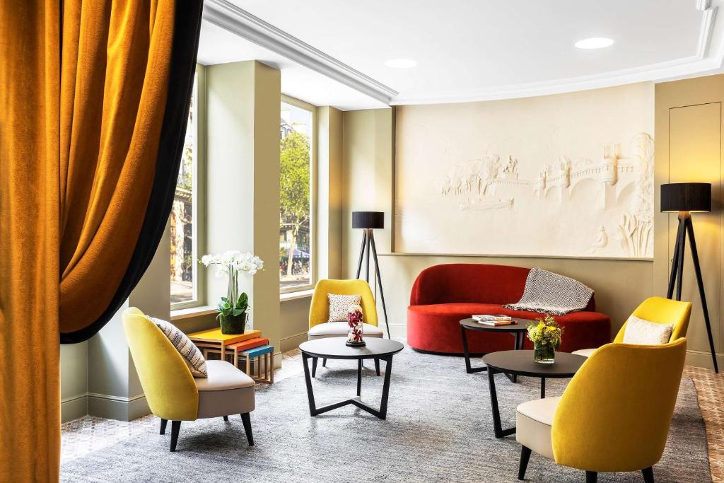 a living room with yellow and red chairs and tables at Hotel Ducs de Bourgogne in Paris