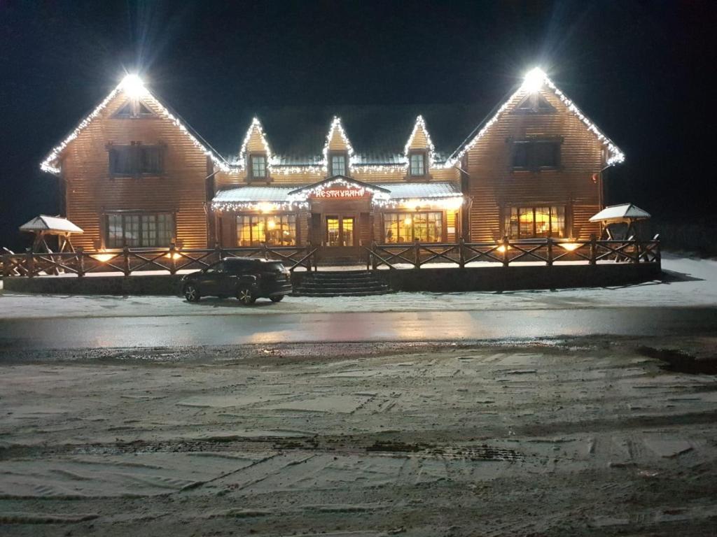 una grande casa in legno con un'auto parcheggiata di fronte di HANUL TENTEA a Săcel