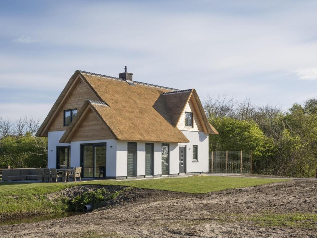 une maison blanche avec un toit marron dans l'établissement Ritzy villa in De Cocksdorp Texel with terrace, à De Cocksdorp
