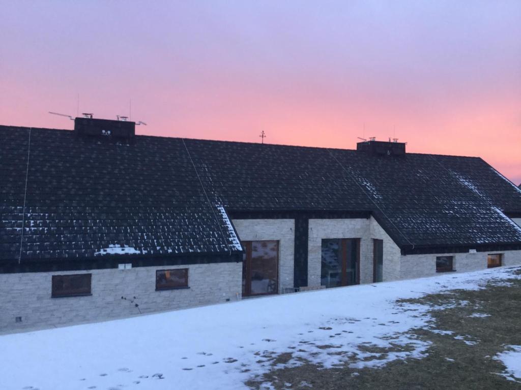 ein Haus mit Schnee auf dem Dach bei Sonnenuntergang in der Unterkunft St. Prokop Luxury Apartments 254 in Boží Dar