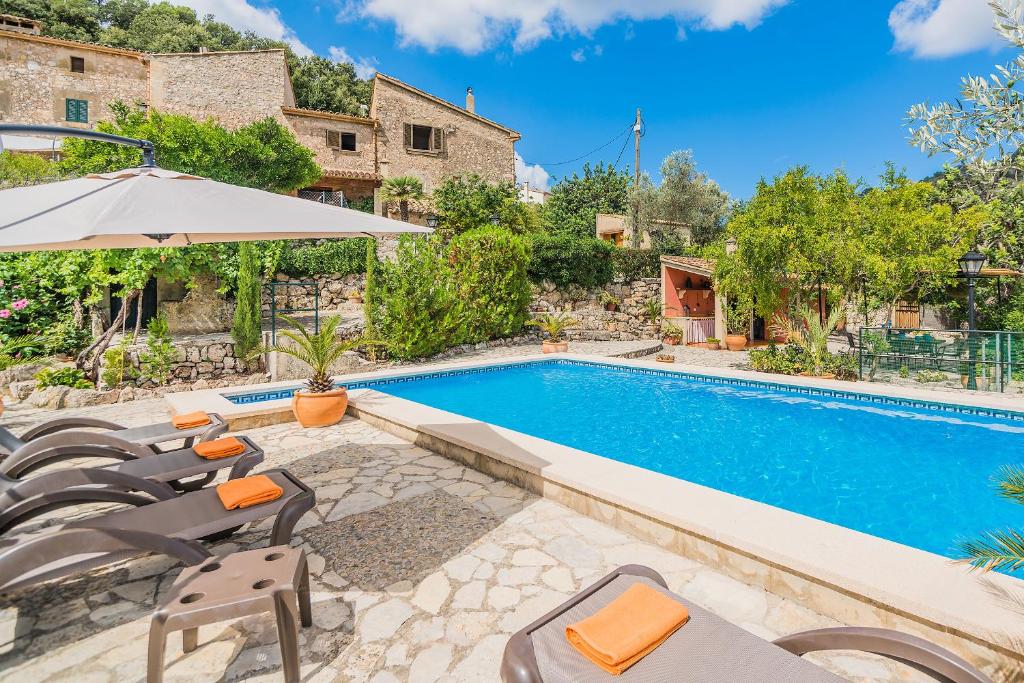 a swimming pool with chairs and an umbrella at Villa Can Pau By SunVillas Mallorca in Pollença