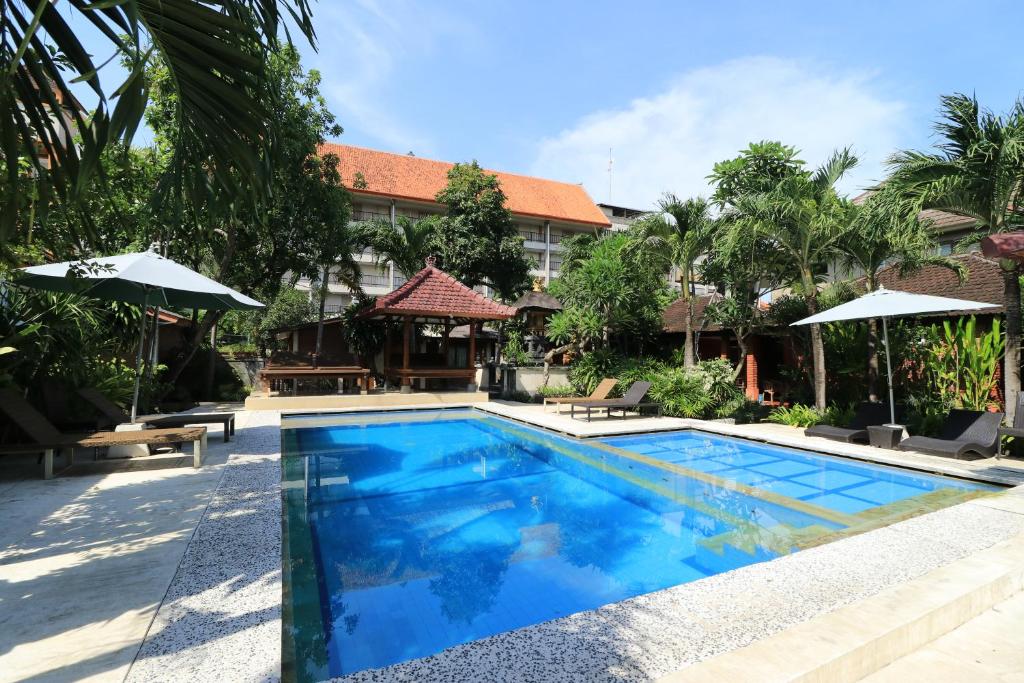 a swimming pool in front of a building at Ayu Lili Garden Hotel Kuta in Kuta