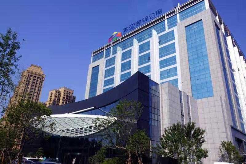 a tall building with a sign on top of it at Yantai Meiya International ApartHotel (Previous Ramada Plaza) in Yantai