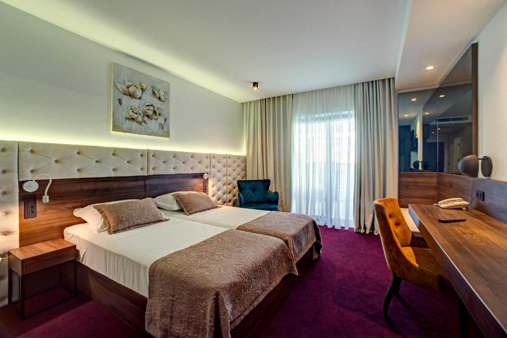 ヴォディツェにあるHotel Scala d'Oroの大きなベッドとデスクが備わるホテルルームです。