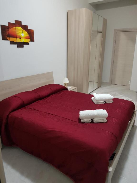 a bedroom with a red bed with two towels on it at Sweet Home in Floridia