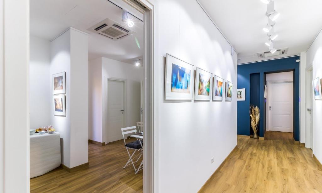 um corredor com paredes brancas e pinturas nas paredes em OTTO Rooms & Photogallery em Roma