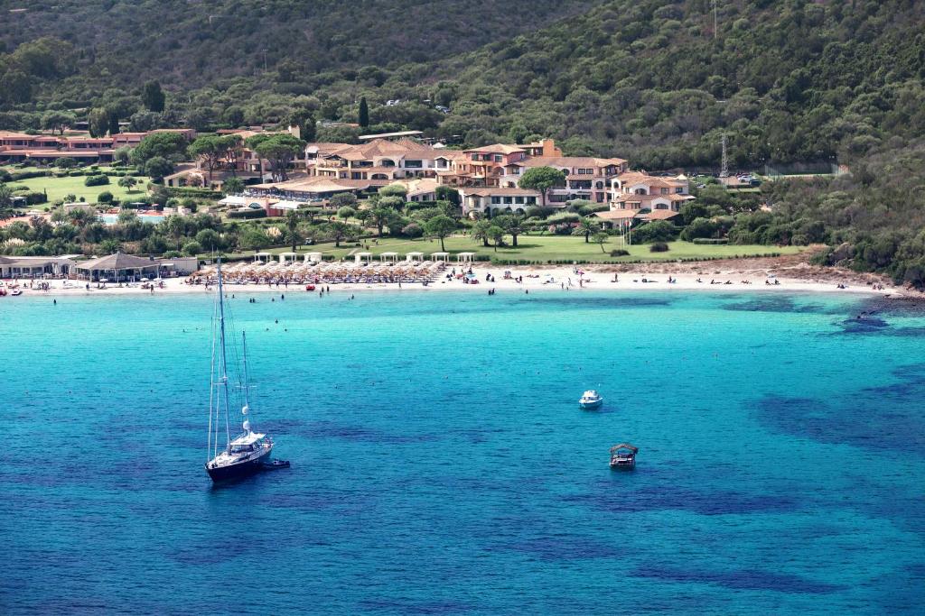 a sail boat in the water near a beach at Hotel Abi d'Oru in Porto Rotondo