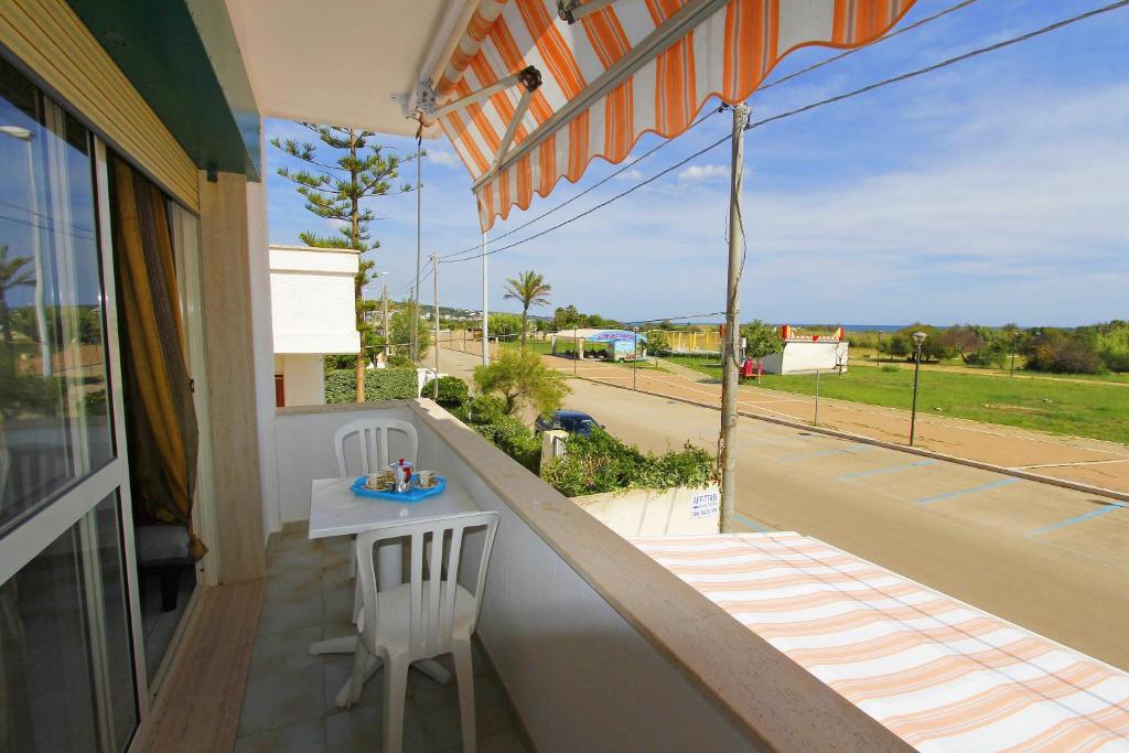 balcone con tavolo e vista sulla strada di Appartamento fronte spiaggia a Marina di Pescoluse