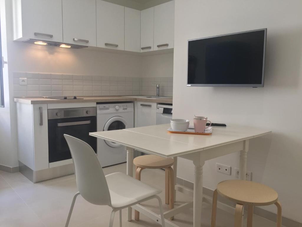 a kitchen with a table and chairs and a tv on the wall at 2 rue Palmaro à côté de la plage in Menton