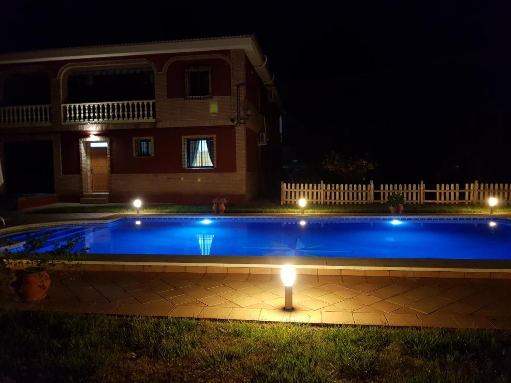 una piscina con luci di fronte a una casa di notte di El Manantial B&B a El Higuerón